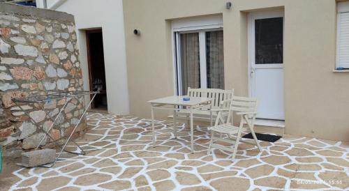 White Lotus seaside apartment في كينيون: فناء مع طاولة وكراسي وجدار حجري