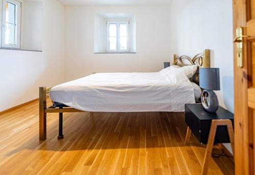 a bed in a white room with a wooden floor at Pop Maison in Mendrisio