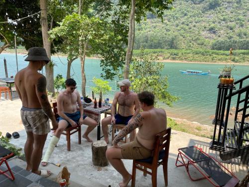 a group of men sitting around a table by the water at Little Rock Homestay in Phong Nha