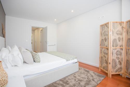 een witte slaapkamer met een bed en een kast bij Inviting - Douro Vista Apartments in Valbom