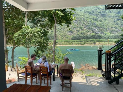 a group of people sitting at a table looking at the water at Little Rock Homestay in Phong Nha