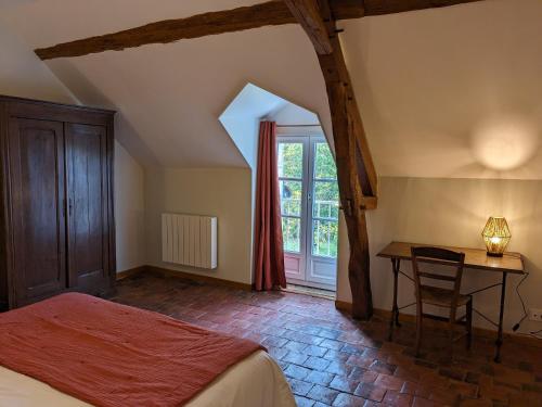Schlafzimmer mit einem Bett, einem Schreibtisch und einem Fenster in der Unterkunft Maison dans belle longère - La Serrerie in Thenay