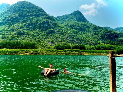 two people in the water in a lake with mountains at Little Rock Homestay in Phong Nha