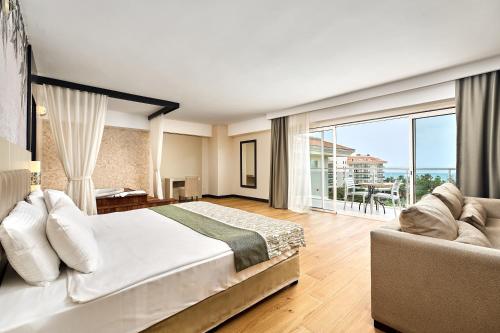 a bedroom with a large bed and a couch at Seaden Sea World Resort & Spa in Kizilagac