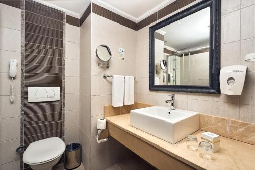 a bathroom with a sink and a toilet and a mirror at Seaden Sea World Resort & Spa in Kizilagac
