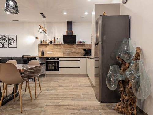 Il comprend une cuisine équipée d'un réfrigérateur et d'une table avec des chaises. dans l'établissement Villa au cœur des Landes, à Soustons