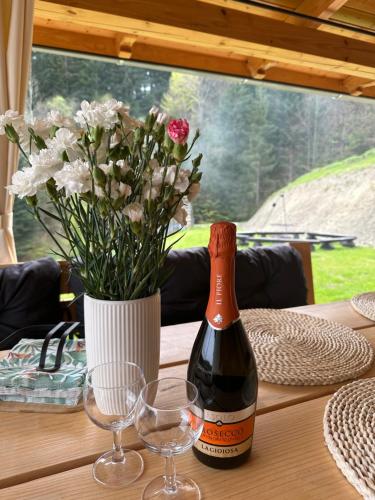 uma garrafa de vinho sentada numa mesa com copos em Rajskie wzgórze słoikowo 