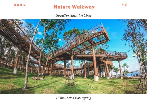 un puente de madera en un parque con árboles en Lay low hostel en Ubon Ratchathani