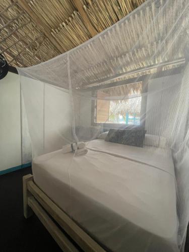 a white bed with a mosquito net in a room at Palenque Beach House in San Onofre