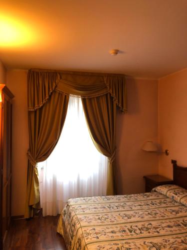 a bedroom with a bed and a window at Villa Felcaro - Relais, Lodge & Restaurant in Cormòns