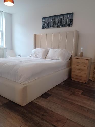 a bedroom with a large white bed and a wooden floor at Q Flat Skyview Central Bradford in Bradford