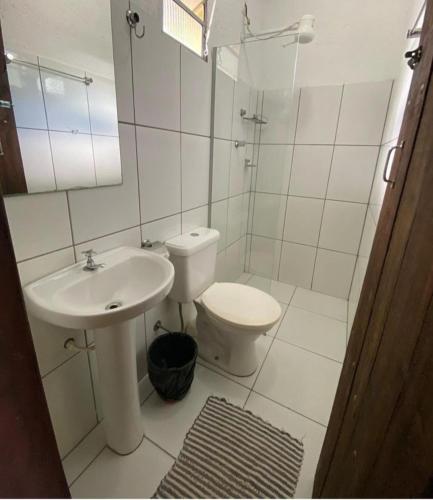 a white bathroom with a sink and a toilet at Pousada Embaubas in Serra do Cipo