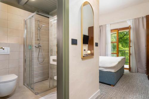 a bathroom with a shower and a toilet and a bed at Boutique Hotel Paradiso in Poreč