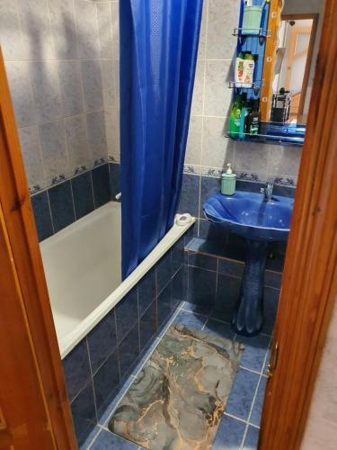 uma casa de banho com um lavatório e um chuveiro com um piso danificado em Уютная квартира в центре города. em Aktau
