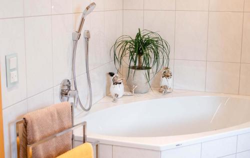 uma banheira branca com uma planta na casa de banho em Ferienloft-Charlotte em Tondorf