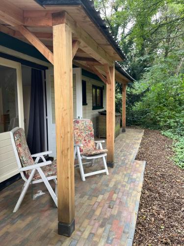 two chairs sitting on a porch of a house at huisje in het bos in Zuidlaren
