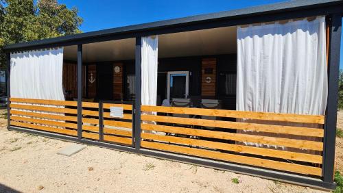 ein Haus mit schwarzem Dach und weißen Vorhängen in der Unterkunft CHARTA mobile home Bimbo in Pirovac