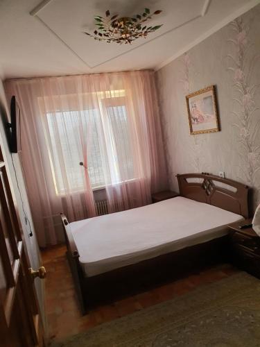 1 dormitorio con cama y ventana en Уютная квартира в центре города., en Aktau