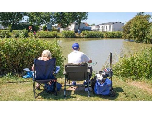 a man and a woman sitting in chairs by a lake at 163 Holiday Resort Unity Brean - Centrally Located Pet Stays Free - Passes Included No Workers sorry in Brean