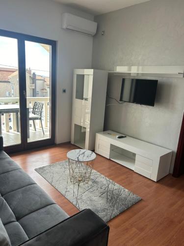 ein Wohnzimmer mit einem Sofa, einem TV und einem Tisch in der Unterkunft Apartmani Baki in Podstrana