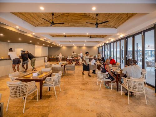 薩拉昆達的住宿－Kombo Beach Resort，餐厅里有人坐在桌子和窗户上