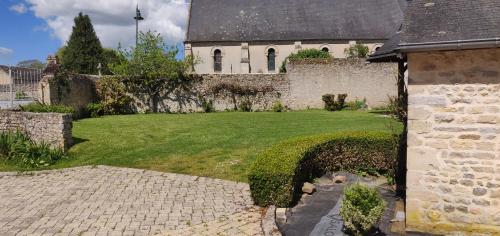 a house with a stone wall and a green yard at Aux belles pierres in Carcagny