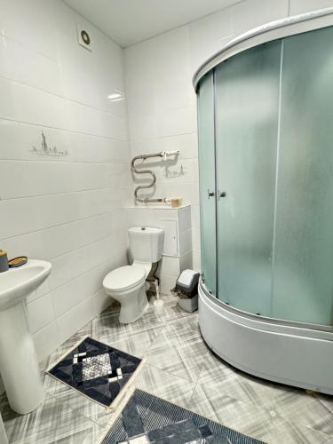 uma casa de banho com uma cabina de duche em vidro e um WC. em Комфортные апартаменты в ЖК Сконур рядом с Жекпе-Жек em Aqtöbe