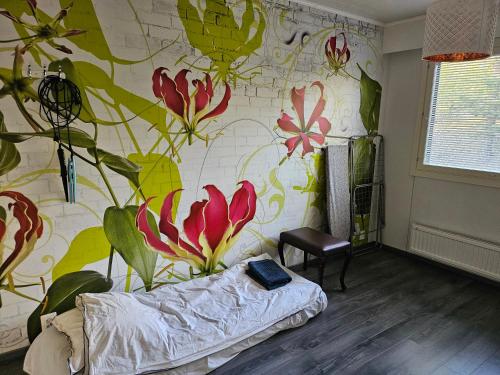 uma sala de estar com um mural de flores na parede em Viihtyisä rivitalokolmio autopaikalla em Kangasala