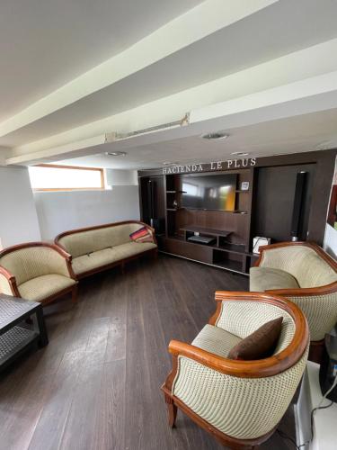 a living room with chairs and a couch and a television at Hacienda Le Plus in Quito