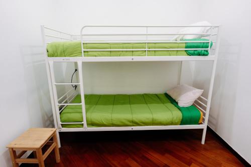 a bunk bed with green sheets and a wooden stool at Palazzo Boemondo in Bari