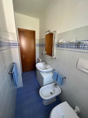 een badkamer met 2 wastafels, een toilet en een spiegel bij Consumella24 in Portoferraio