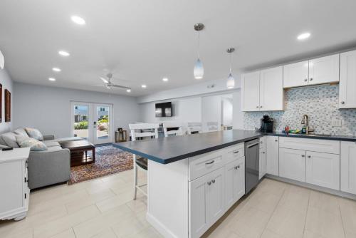 a kitchen with white cabinets and a living room at Heated Pool Home steps to the beach in Fort Myers Beach
