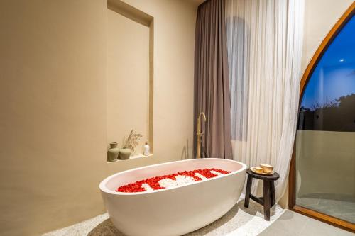 un bagno con vasca bianca piena di fiori rossi di Amani Villas: New, Luxury, Mediterranean, Private Pool, Canggu a Canggu