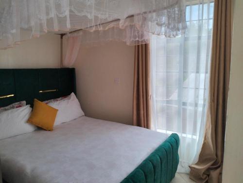 a bedroom with a bed and a window with curtains at Yala comfy homes in Kitengela 