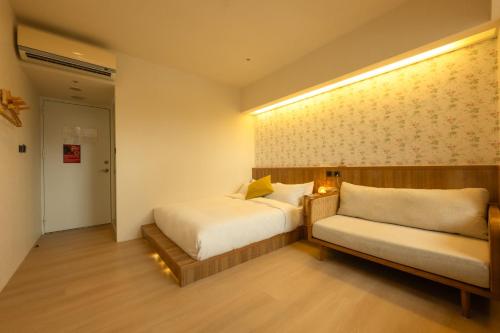 a bedroom with a bed and a couch in it at Cat Tail Pocket Inn in Taipei