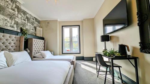 a hotel room with two beds and a desk and a television at INNit Bliss in Brighton & Hove