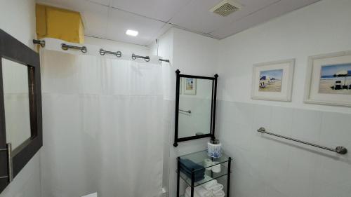 a white bathroom with a shower and a mirror at BUNKER BEACH @ ISLA VERDE / Beach Front in San Juan