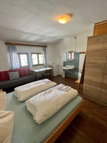 a bedroom with two beds and a living room at SKILL Mountain Lodge - Ski und Bike Hostel im Sommer mit JOKER CARD in Saalbach Hinterglemm