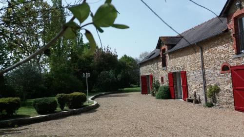 een bakstenen gebouw met rode deuren en een oprit bij Brimbilly, maison de charme in Guenrouet