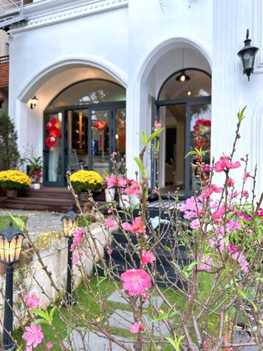 a white house with pink flowers in front of it at Moon Homestay in Thôn Kim Long (1)