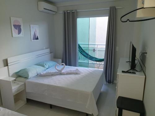 a bedroom with a bed and a television and a window at AP encantador na Praia do Forte! (208) in Cabo Frio