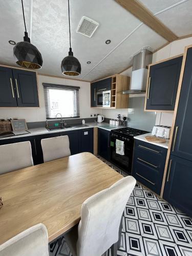 a kitchen with a wooden table and chairs in it at The Luxe Lodge, Skipsea Sands Bridlington in Ulrome