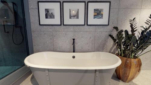 a white tub in a bathroom with four pictures on the wall at voco Manchester - City Centre by IHG in Manchester