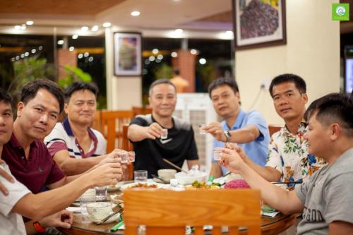 een groep mannen die rond een tafel zitten te eten bij Khách Sạn Bản Giốc Quây Sơn in Lũng Niêo