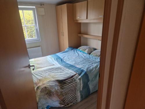 een klein bed in een kleine kamer met een raam bij Camping Goedereede Chalet nr 16 in Goedereede