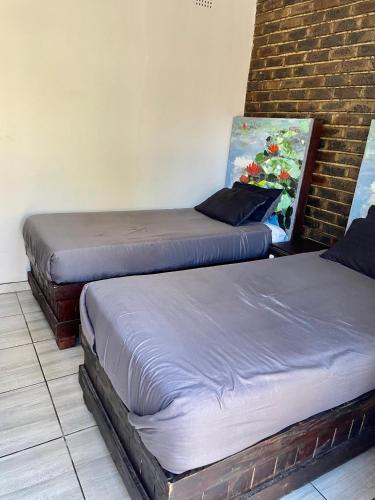 two twin beds in a room with a brick wall at SapzRes at Klerksdorp in Klerksdorp