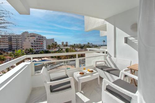 balcón con muebles blancos y vistas a la playa en Apart hotel Ponderosa with a pool & view, studio 226, en Playa Fañabe