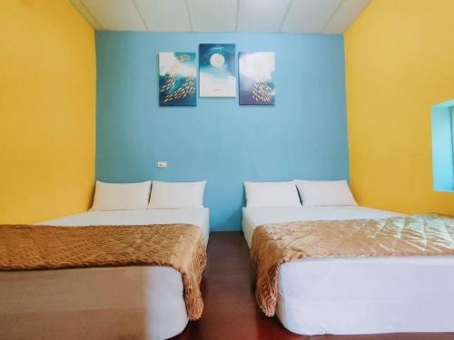 two beds in a room with blue and yellow walls at 小琉球陽光藍海民宿 in Xiaoliuqiu
