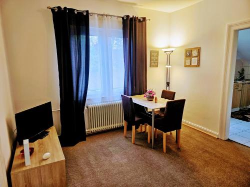 a living room with a table with chairs and a television at Apartment Jackie in Bielefeld