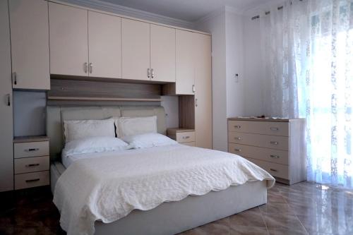 um quarto com uma cama branca e armários brancos em Meti Apartment em Durrës